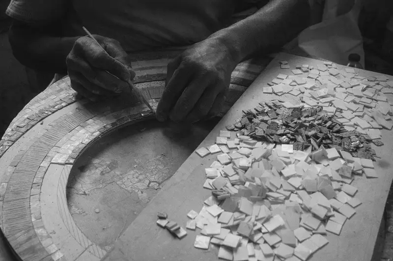 Hände setzen ein Mosaik aus kleinen Fliesen